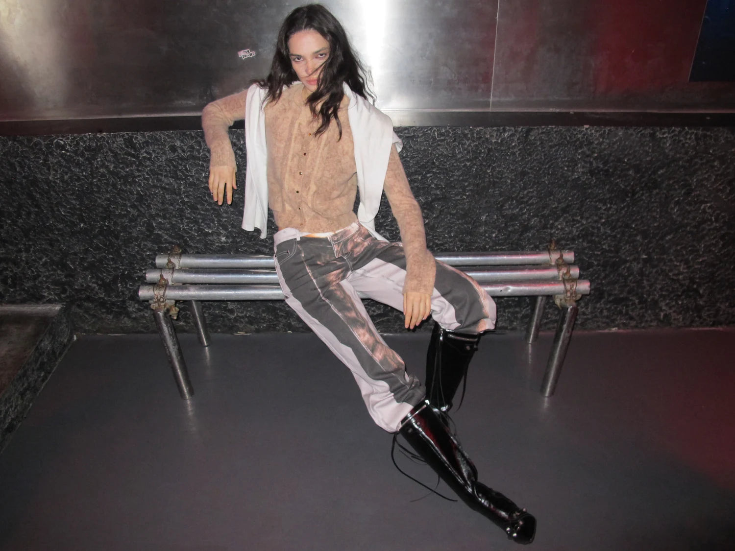 AURA LAND textured vest, relaxed trousers and tall boots beside a public bench